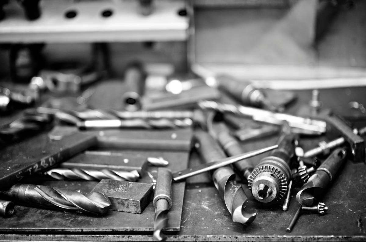Workshop setup for diy metal wood industrial furniture showing tools, steel stock, and finished table